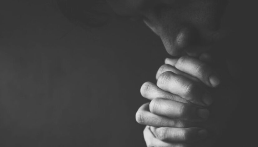 Praying Man Against Dark Background With Copy Space