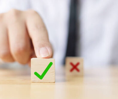 Hand of a businessman chooses checkmark and x sign symbol on wooden cube block