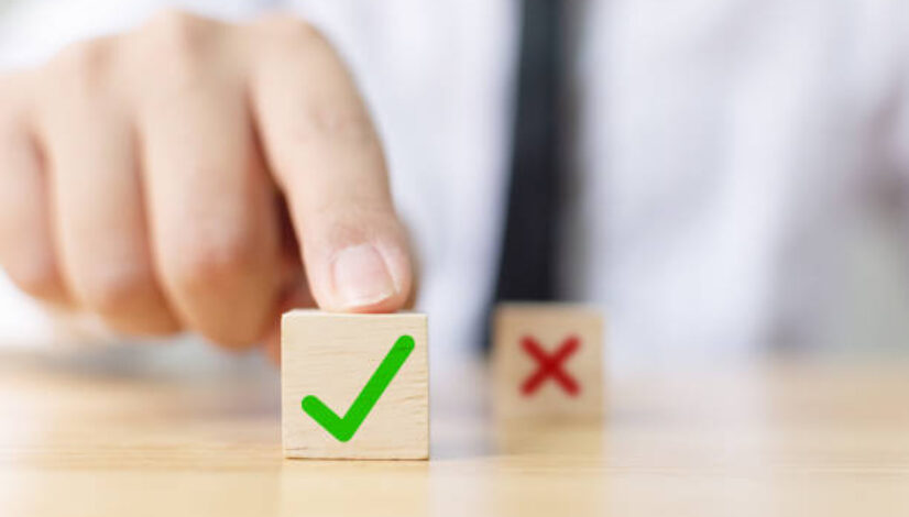 Hand of a businessman chooses checkmark and x sign symbol on wooden cube block